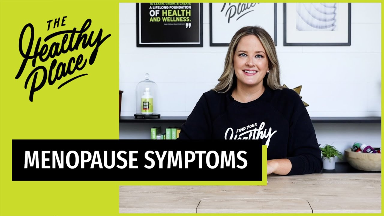 A video thumbnail from "The Healthy Place" featuring a smiling woman at a table with bold text reading "MENOPAUSE SYMPTOMS" and the brand’s logo on a lime green background.