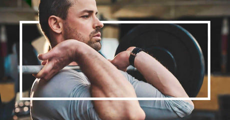 A man is engrossed in his workout, lifting a heavy barbell with determination. The concentration on his face and the flex of his biceps underscore the intensity of his exercise routine.