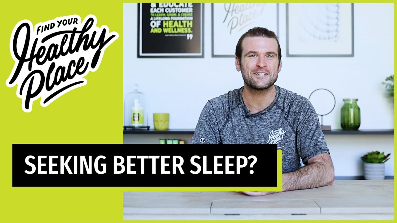 A man in a gray 'Find Your Healthy Place' shirt sits at a table with a wellness-themed background. Text overlay reads 'SEEKING BETTER SLEEP?'