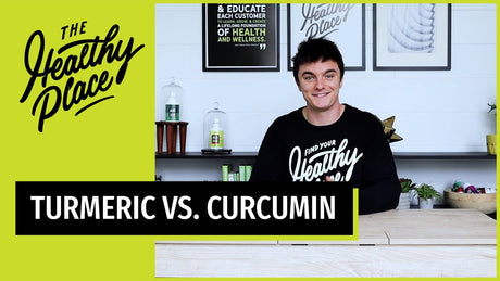 A young man sits at a wooden table. He is wearing a black tee that reads "Find Your Healthy Place." A banner graphic below him reads "Turmeric vs Curcumin."