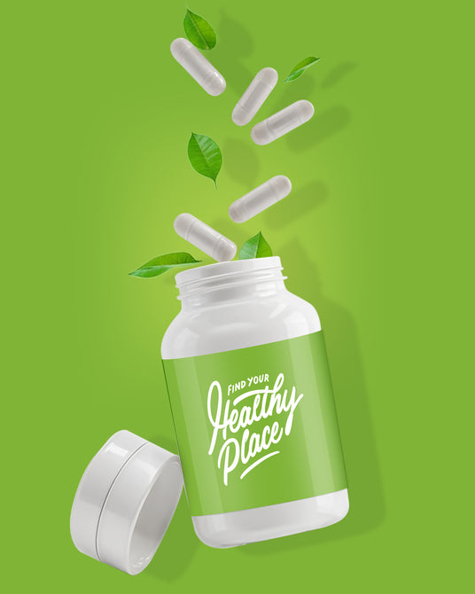 A white supplement bottle with a green label that reads "Find Your Healthy Place," tilted with its cap off, spilling white capsules and green leaves against a matching green background, symbolizing natural health and wellness.