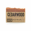 A natural bar of cedarwood soap, 3.5 ounces 99 grams, with a rustic brown label describing its purifying and exfoliating properties, featuring the text "AWSB Scratch Made Soap."