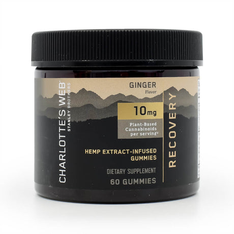 Jar of Charlotte’s Web Recovery Gummies in ginger flavor, containing 60 gummies. Label states 10 mg of plant-based cannabinoids per serving, with "Hemp Extract-Infused Gummies" and "Recovery" highlighted in gold and white text. Packaging features a black and gold mountain design.