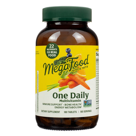 A larger brown bottle of "MegaFood One Daily" multivitamin with 180 tablets, showcasing 22 nutrients plus real food. The label is bright yellow and green with illustrations of carrots, broccoli, celery, and a blueberry, highlighting benefits like immune support, bone health, and energy metabolism.