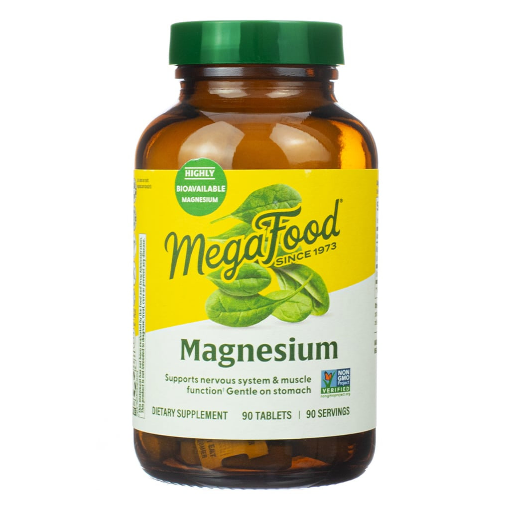 Front-facing bottle of MegaFood Magnesium dietary supplement containing 90 tablets, labeled to support nervous system and muscle function. The amber bottle features a yellow and white label with green leafy imagery and is marked as "highly bioavailable" and "Non-GMO Project Verified."