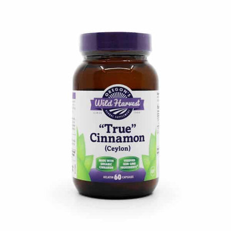 Amber bottle with a purple lid labeled “Oregon’s Wild Harvest True Cinnamon (Ceylon).” The label notes it's made with organic cinnamon, verified non-GMO, and contains 60 gelatin capsules. Features green leaf graphics and a white and purple color scheme.