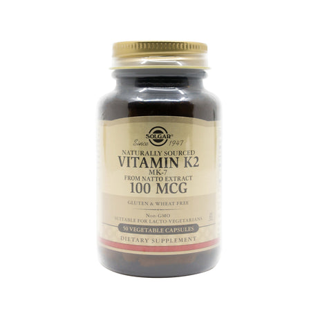 Dark amber bottle of Solgar Vitamin K2 MK-7, labeled “Naturally Sourced from Natto Extract, 100 MCG.” The label highlights key features including gluten and wheat free, non-GMO, suitable for lacto-vegetarians, and contains 50 vegetable capsules.
