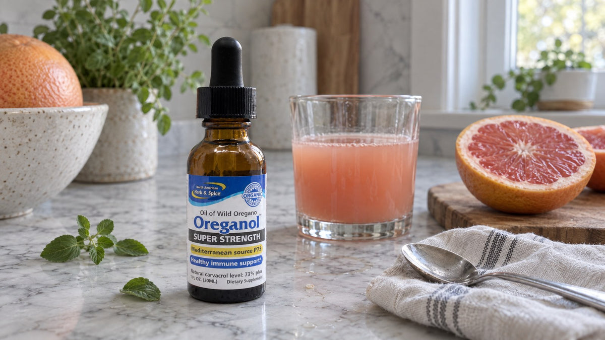 Super Strength Oreganol P73 bottle on a marble counter beside a glass of grapefruit juice and a halved grapefruit