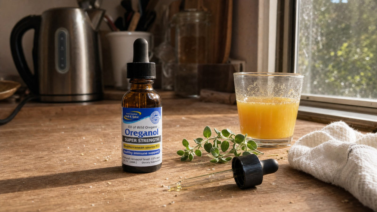 Bottle of North American Herb & Spice Super Strength Oreganol P73 oil on a kitchen counter in morning light with orange juice and fresh oregano