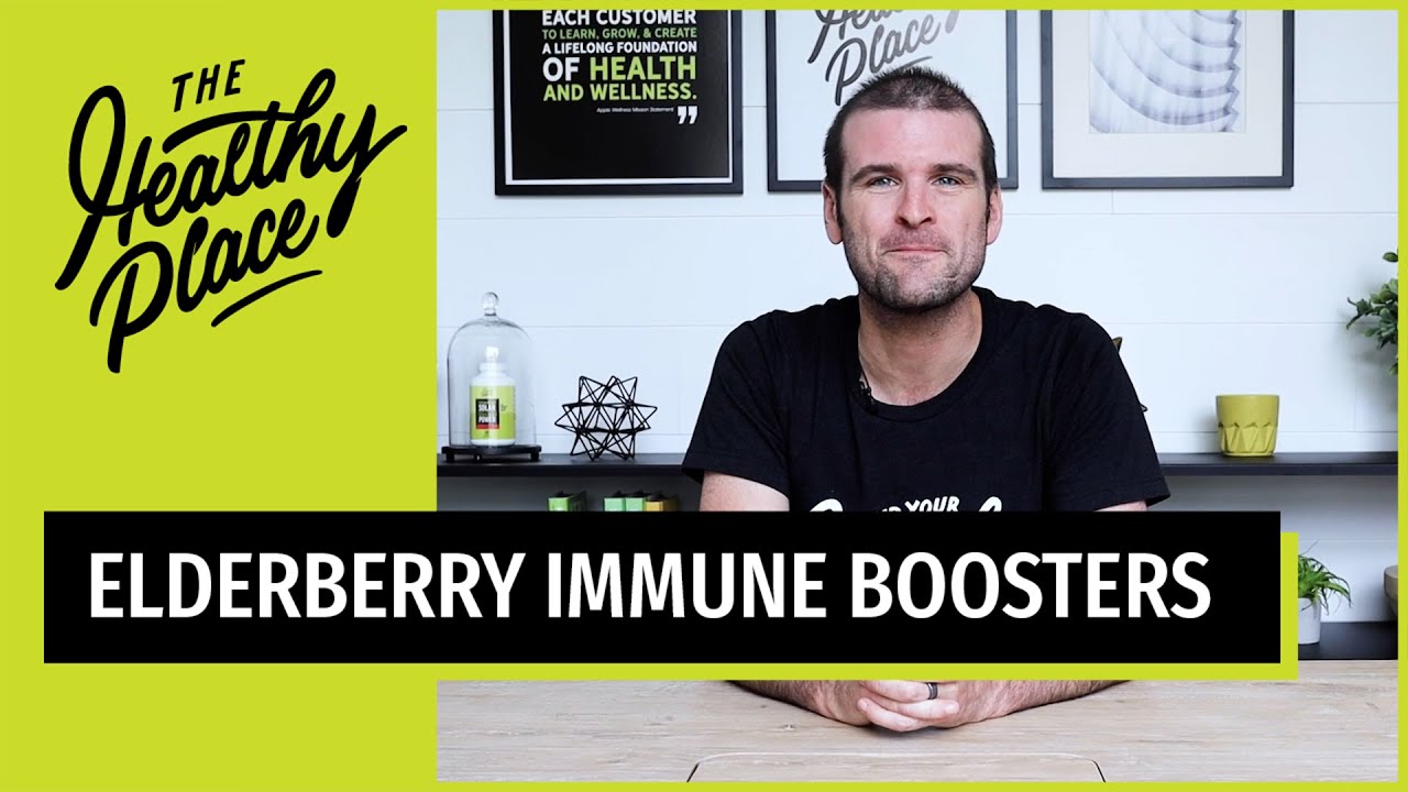 A man in a black 'Find Your Healthy Place' shirt sits at a table with a wellness-themed background. Text overlay reads 'ELDERBERRY IMMUNE BOOSTERS.'