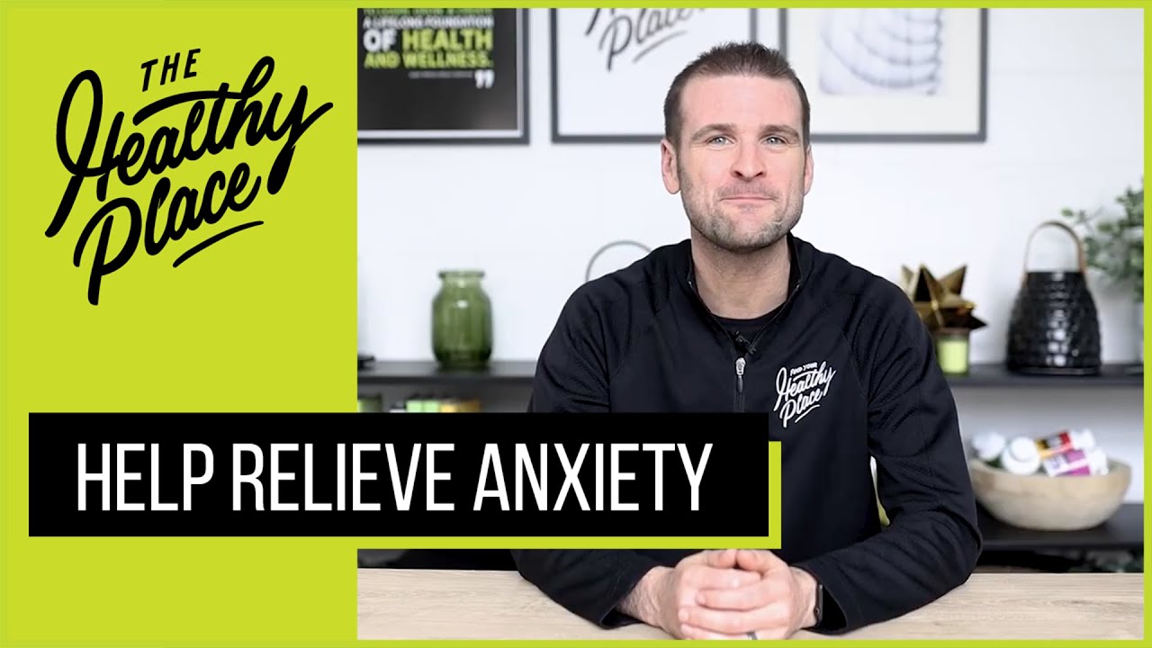 Man in a 'Find Your Healthy Place' jacket sits at a table with a wellness-themed background. Bold text overlay reads 'HELP RELIEVE ANXIETY.'