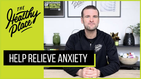 Man in a 'Find Your Healthy Place' jacket sits at a table with a wellness-themed background. Bold text overlay reads 'HELP RELIEVE ANXIETY.'