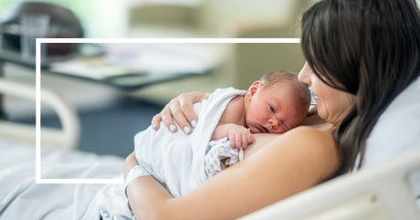 A tender moment of a mother cradling her newborn baby against her chest in a hospital bed, with soft natural lighting.