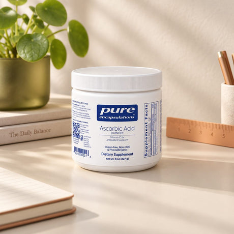 Pure Encapsulations Ascorbic Acid Powder 8 oz container on a desk beside a plant, books and a ruler