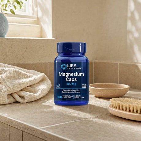 Woman holding Life Extension Magnesium Caps 500 mg bottle beside a glass of water