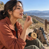 Chuga Pure Himalayan Shilajit Resin taken from the monkey spoon by a woman on a hiking trail, jar in her other hand