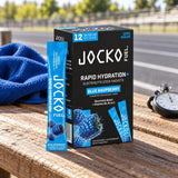 JOCKO FUEL Rapid Hydration+ Blue Raspberry box and stick packet on a wooden bench by a track, towel and stopwatch