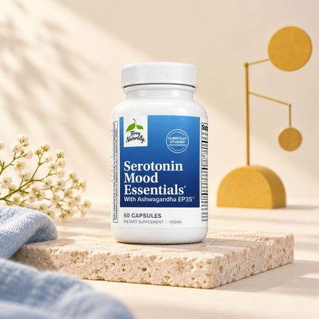 Terry Naturally Serotonin Mood Essentials bottle on a stone block with small white flowers and a gold sculpture