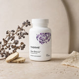Woman in her 40s holding Thorne Research Meta-Balance Capsules during a morning wellness routine