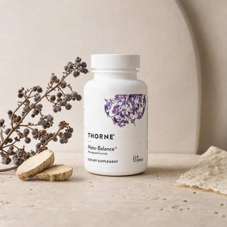 Woman in her 40s holding Thorne Research Meta-Balance Capsules during a morning wellness routine