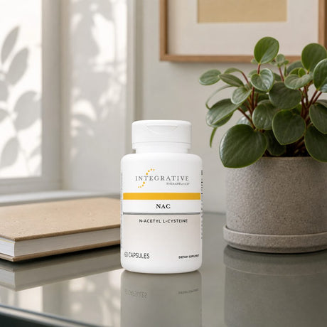 Integrative Therapeutics NAC Capsules bottle on a counter beside a glass of water