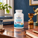 Nordic Naturals Ultimate Omega + CoQ10 Lemon bottle on a wooden desk beside books and an hourglass