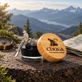 Chuga Pure Himalayan Shilajit Resin jar and monkey spoon on a rock ledge with a compass and map, mountains behind
