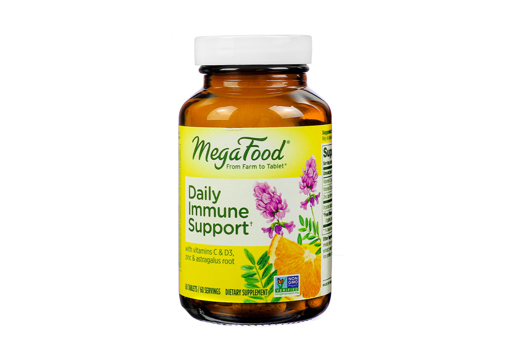 Amber glass bottle of MegaFood Daily Immune Support tablets with a yellow label displaying botanical illustrations of astragalus root, citrus, and herbs. Promotes immune health with vitamins C & D3, zinc, and astragalus root; includes 60 tablets (60 servings), and features the Non-GMO Project Verified seal.
