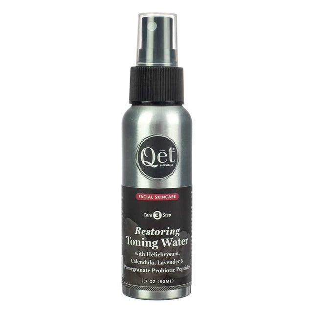 A sleek metallic spray bottle labeled "Qet Botanicals Restoring Toning Water" with ingredients like helichrysum, calendula, lavender, and pomegranate probiotic peptides. Designed for facial skincare as part of a three-step care routine.