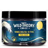 Clear plastic jar with a black lid labeled “Wild Theory CBD Co Tidal Wave,” containing 60 blueberry lemonade flavored gummies with 10 mg Delta-9 THC and 0 mg CBD per gummy. The packaging features a night sky, a moon, and a crashing wave illustration, with a net weight of 9.3 oz (264g).