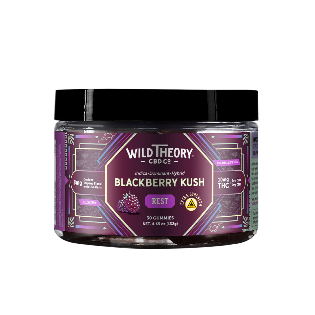 A jar of Wild Theory CBD Co. REST Blackberry Kush gummies with a purple geometric label. It features a bold white brand logo at the top, with "Indica-Dominant Hybrid" below it. The flavor "Blackberry Kush" is prominently displayed in white text, along with the word "REST" in a purple box. Additional details include "Extra Strength" in a yellow badge, "8mg Custom Terpene Blend with Live Resin," and dosage information: "10mg THC (2mg CBD, 7mg CBN)." The container holds "30 Gummies" with a net weight of "4.65 