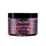 A jar of Wild Theory CBD Co. REST Blackberry Kush gummies with a purple geometric label. It features a bold white brand logo at the top, with "Indica-Dominant Hybrid" below it. The flavor "Blackberry Kush" is prominently displayed in white text, along with the word "REST" in a purple box. Additional details include "Extra Strength" in a yellow badge, "8mg Custom Terpene Blend with Live Resin," and dosage information: "10mg THC (2mg CBD, 7mg CBN)." The container holds "30 Gummies" with a net weight of "4.65 