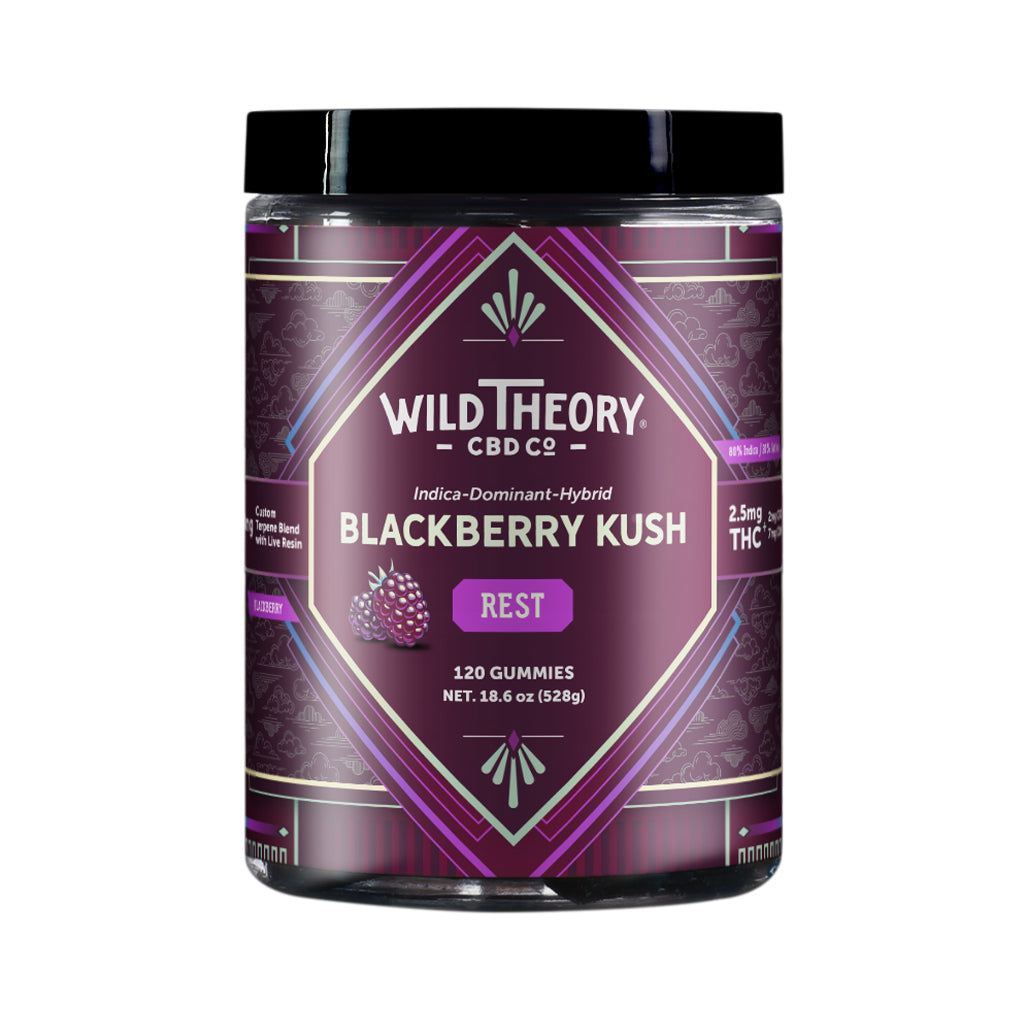 A tall jar of Wild Theory CBD Co. REST Blackberry Kush gummies, featuring a deep purple label with a symmetrical geometric design. The Wild Theory CBD Co. logo is displayed at the top, with "Indica-Dominant Hybrid" and the product name "Blackberry Kush" written below. The label highlights "REST" in a purple box, "8mg Custom Terpene Blend with Live Resin," and dosage details of "2.5mg THC (2mg CBD, 7mg CBN)" per serving. The jar contains "120 Gummies" with a net weight of "18.6 oz (528g)." Additional icons o