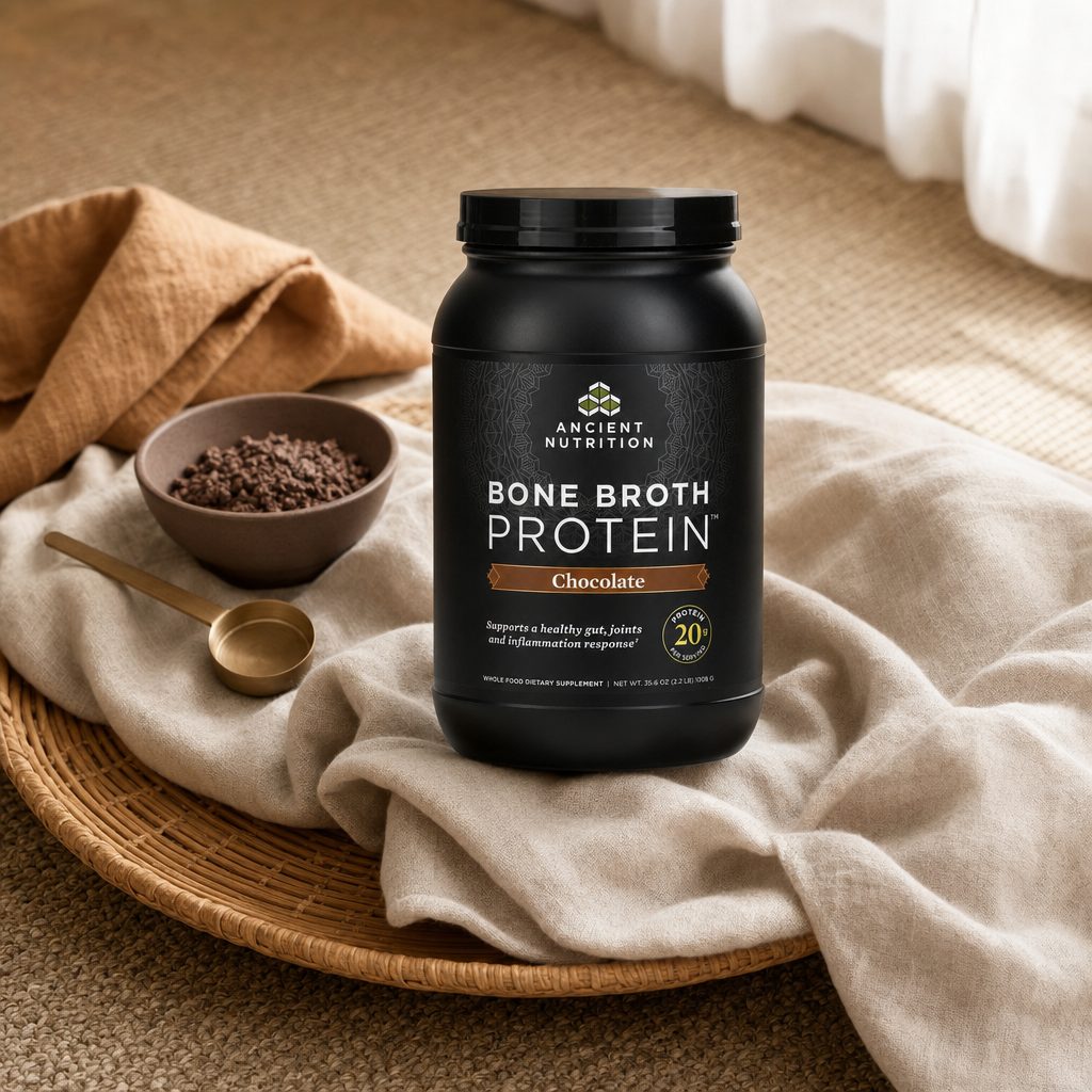 Ancient Nutrition Bone Broth Protein Chocolate tub with scoop and mixed chocolate drink
