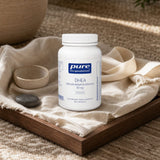 Pure Encapsulations DHEA 10 mg bottle beside a glass of water on a counter