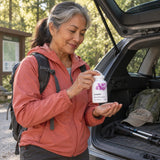 Thorne Advanced Bone Support bottle held by a woman with a backpack at an open car trunk near a trailhead