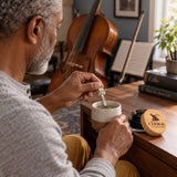 Chuga Pure Himalayan Shilajit Resin stirred into a mug with the monkey spoon by a man at a desk, jar beside him