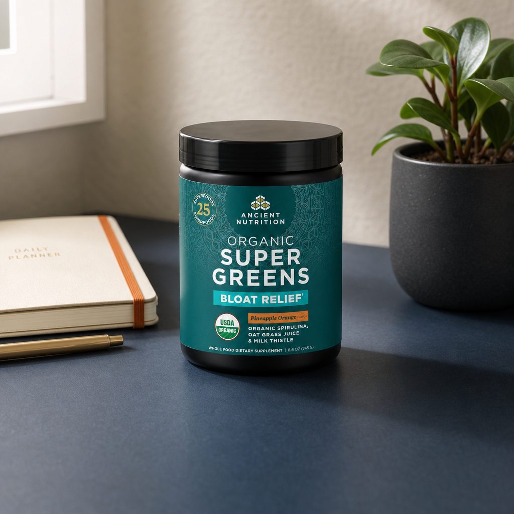Ancient Nutrition Organic SuperGreens Bloat Relief Pineapple Orange tub beside a prepared greens drink
