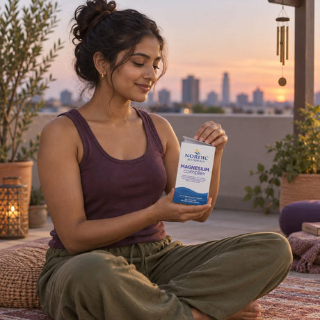 Nordic Naturals Magnesium Complex box held by a woman sitting cross-legged on a rooftop at sunset