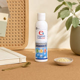 Empirical Labs Liposomal C bottle on a kitchen counter with juice glass