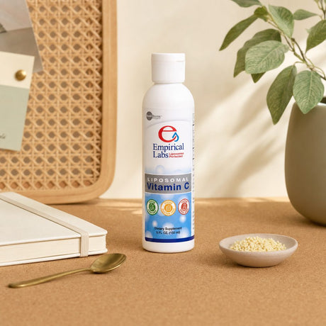 Empirical Labs Liposomal C bottle on a kitchen counter with juice glass