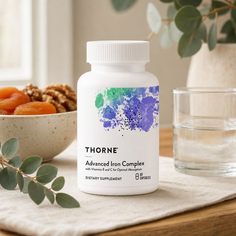Thorne Advanced Iron Complex on warm oak counter with dried apricots, pumpkin seeds, and a glass of water