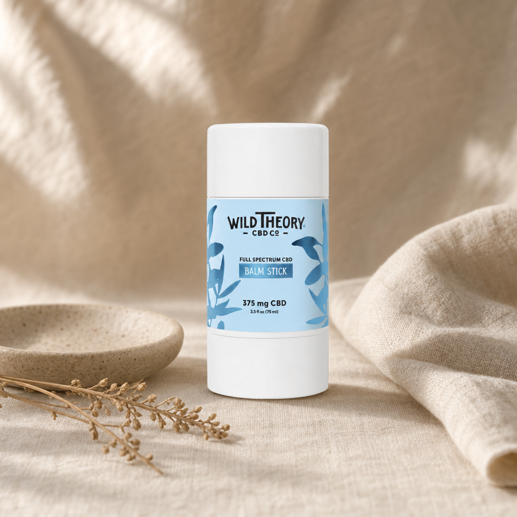 Wild Theory Full Spectrum CBD Balm Stick 375mg twist-up applicator on warm linen with ceramic dish and dried botanical sprig