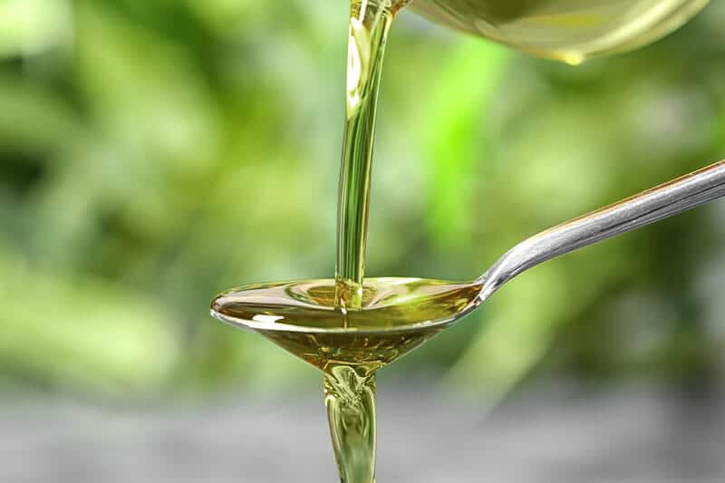 a spoon pouring oil onto a spoon